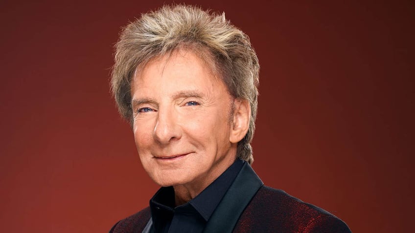 Barry Manilow in a red velvet suit soft smiles