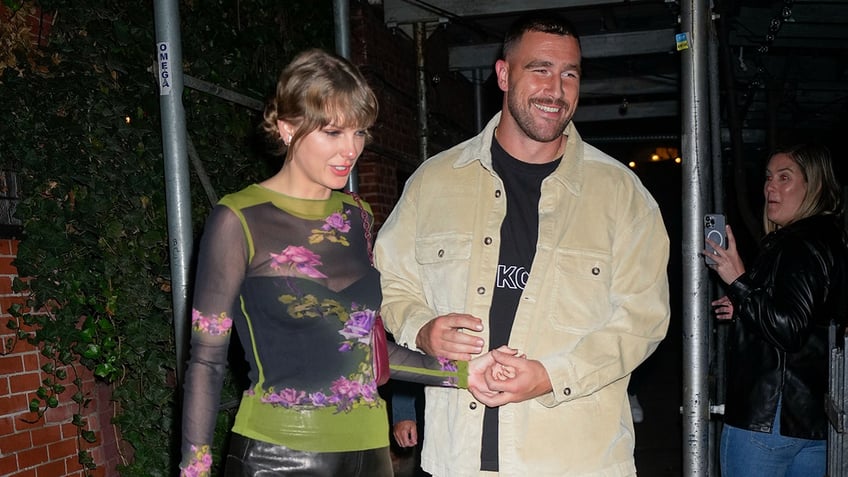 Taylor Swift in a green printed top walks with Travis Kelce in a tan jacket in New York City