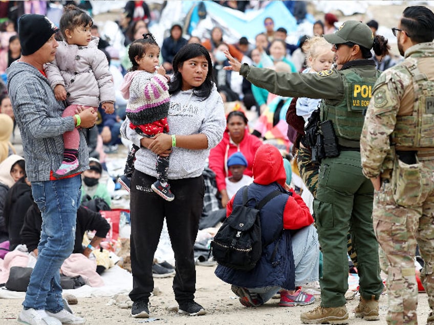 SAN DIEGO, CALIFORNIA - MAY 13: A U.S. Border Patrol agent (2nd R) speaks to immigrants before they are transported from a makeshift camp amongst border walls, between the U.S. and Mexico, on May 13, 2023 as seen from San Diego, California. Some of the immigrants at the open-air camp …