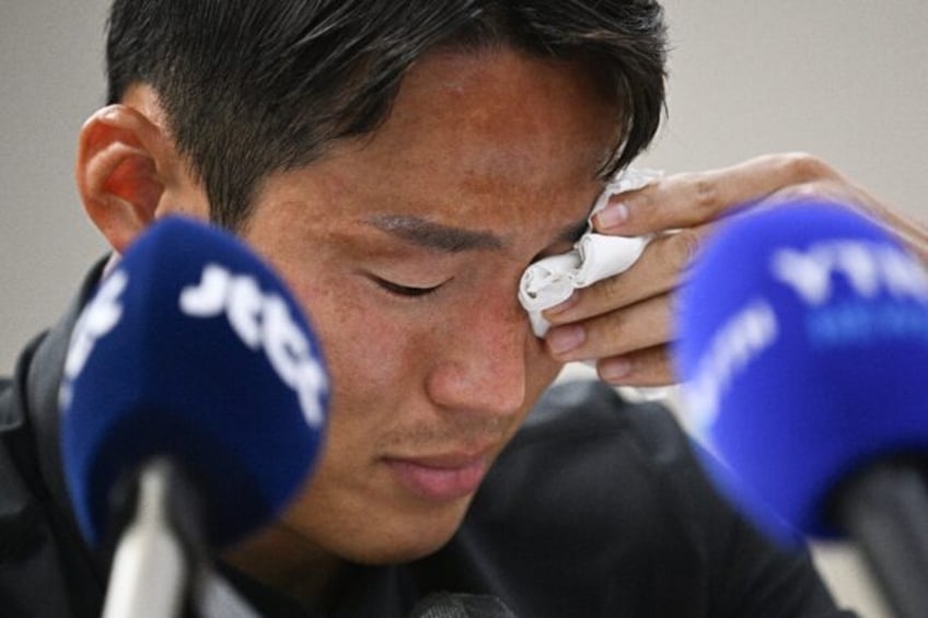 An emotional Son Jun-ho wipes away tears during a press conference where he denied Chinese