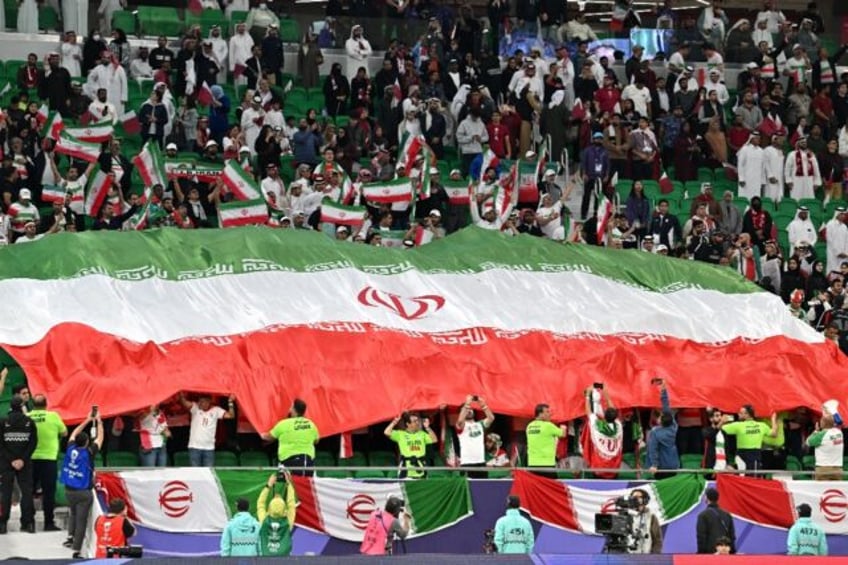 Iranian football fans hold up the national flag during Asian Cup semi-final against Qatar