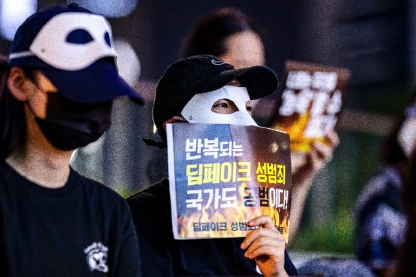 A protester holds a signing reading "Repeated deepfake sex crimes, the state is an accompl