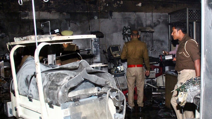 Police officers examine the damaged neonatal intensive care unit after a fire broke out at the Maharani Laxmibai Medical College in Jhansi district