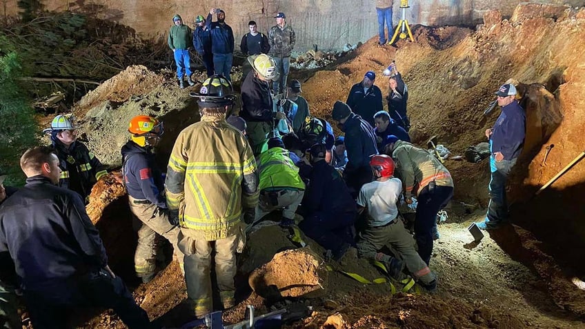rescuers digging out buried backhoe operator