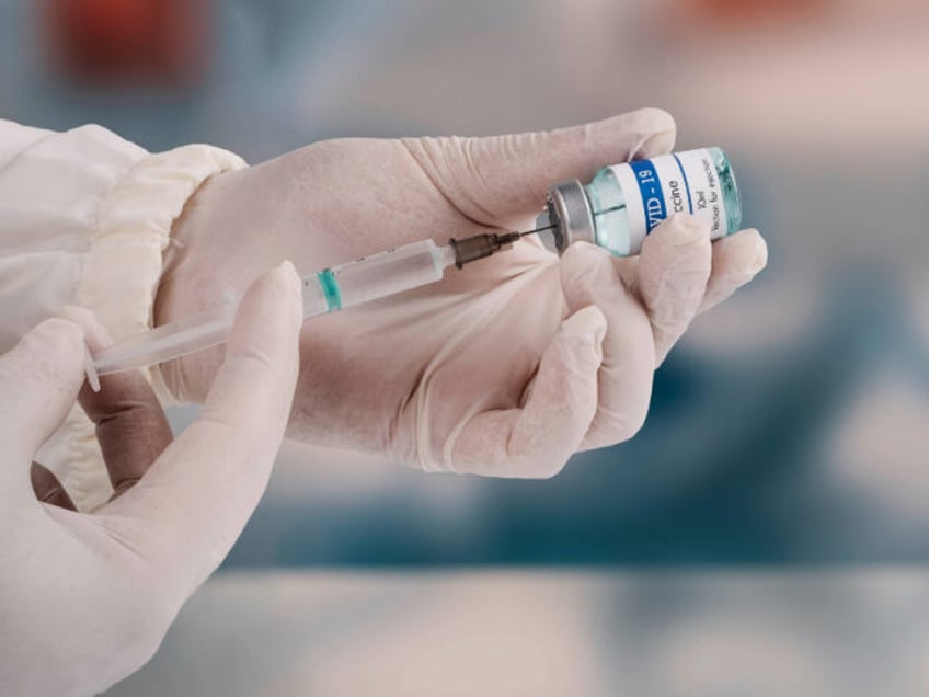 A young doctor in white protective glove is holding a medical syringe and vial - stock pho