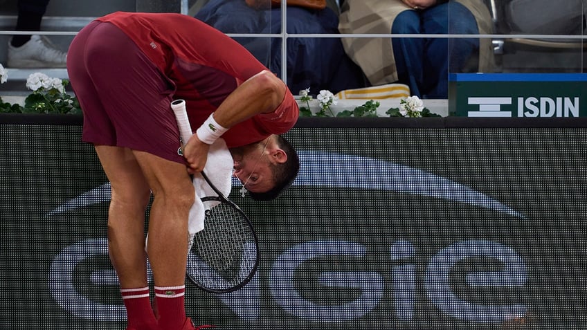 Novak Djokovic dries face with towel