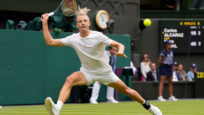 Mark Lajal of Estonia plays a forehand return to Carlos Alcaraz of Spain during their first round match of the Wimbledon tennis championships.