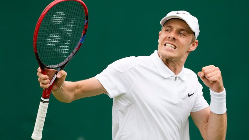 Denis Shapovalov of Canada holds up his racket and pumps his fist in celebration on the court.