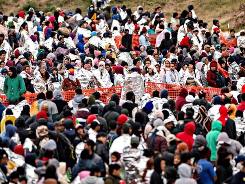 EAGLE PASS, TEXAS - DECEMBER 20: Immigrants wait to be processed at a U.S. Border Patrol transit center after they crossed the border from Mexico on December 20, 2023 in Eagle Pass, Texas. A late-year surge of migrants crossing the U.S.southern border has overwhelmed U.S. immigration officials. (Photo by John …