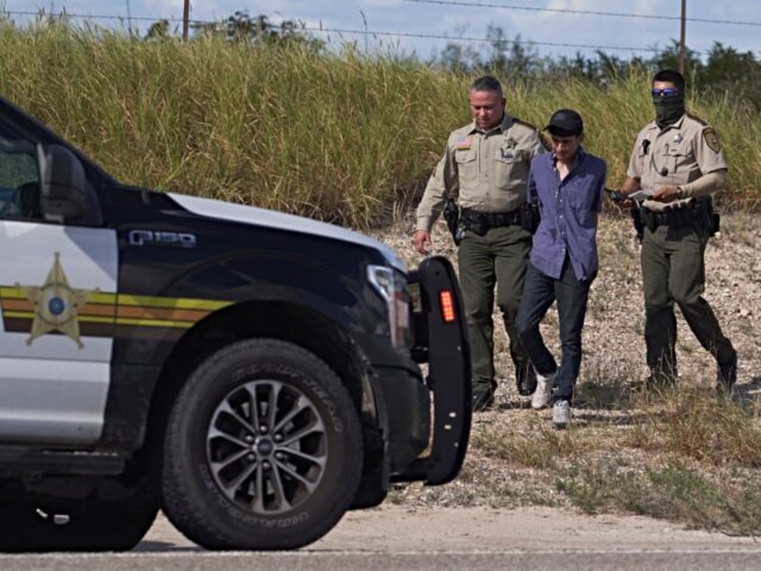 TOPSHOT - A Webb County Sheriffs Officer and US Border Patrol arrest a man smuggling migra