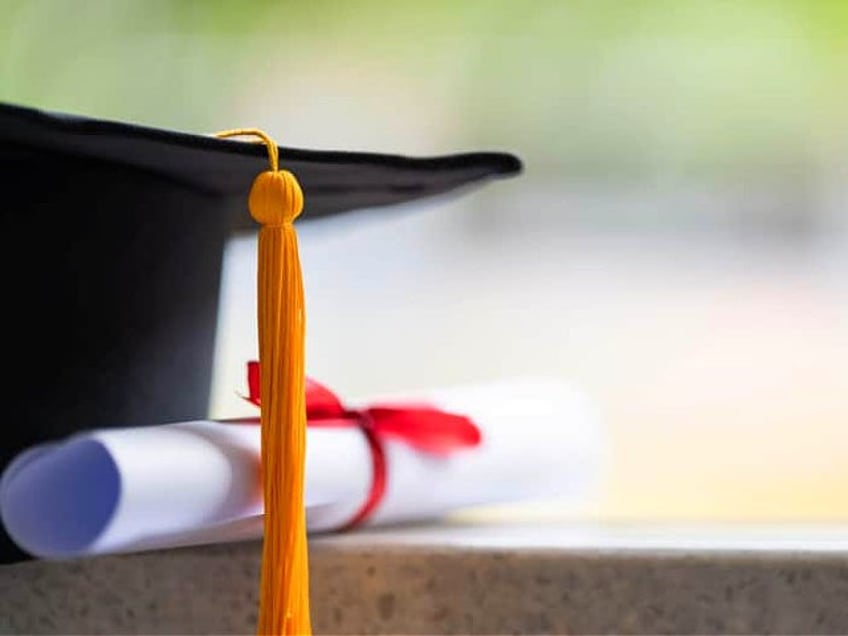 Close-up of a mortarboard and degree certificate put on the table. Education stock photo -