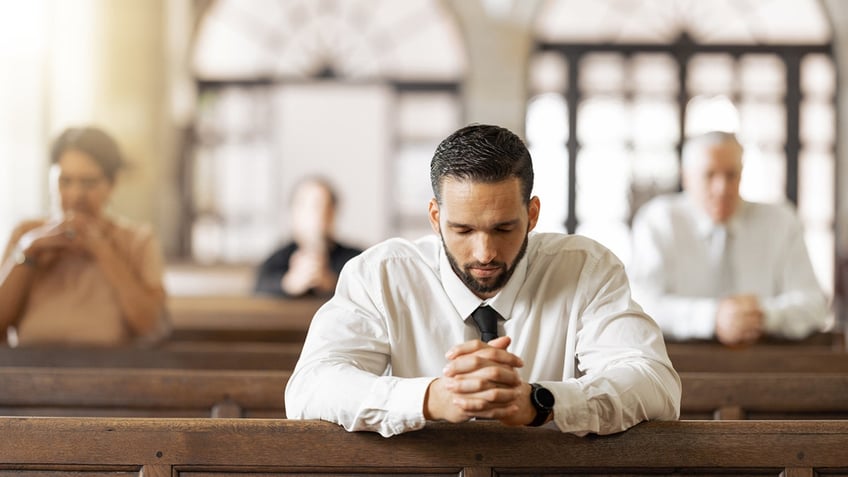 man praying with others praying in the background