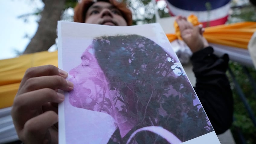 Thai activist holds a portrait of Netiporn Sanesangkhom, a member of the activist group Thaluwang