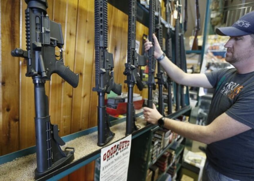 Dordon Brack pulls a semi-automatic AR-15 off the rack at Good Guys Guns & Range on Fe