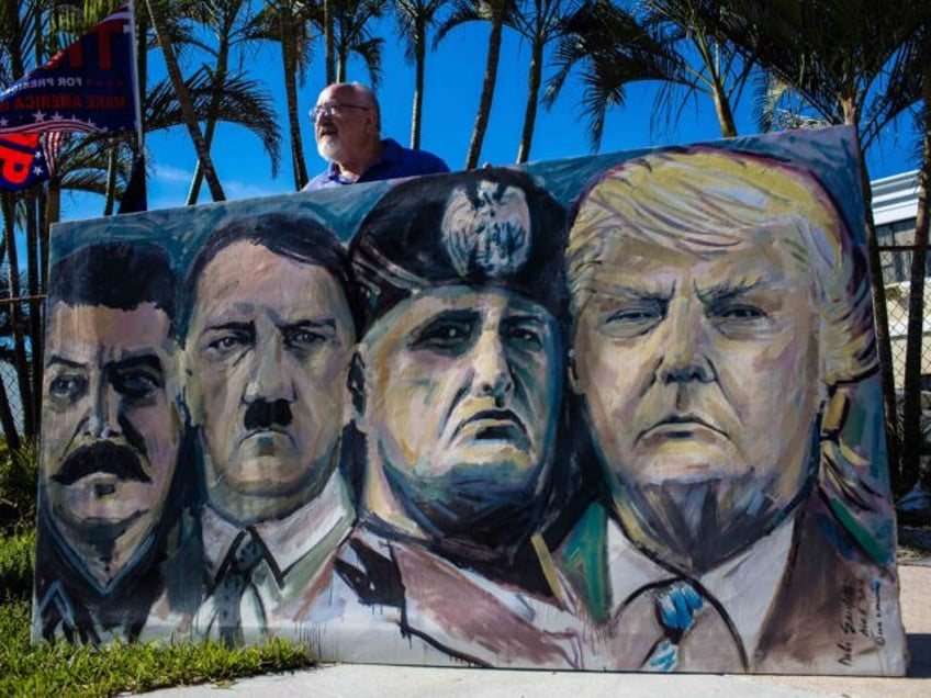 A demonstrator holds a painting featuring the likenesses of Joseph Stalin, from left, Adol