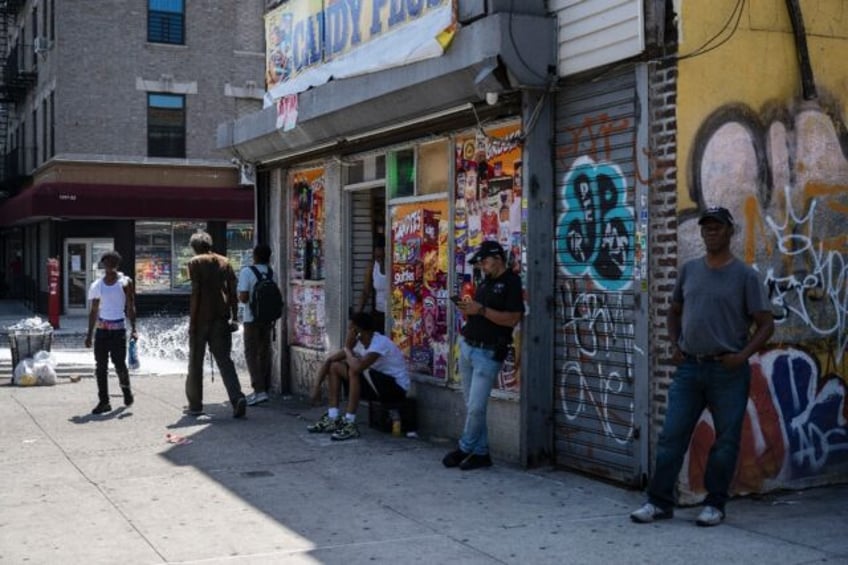 People stand outside a corner store during a summer heat wave in the Bronx borough of New