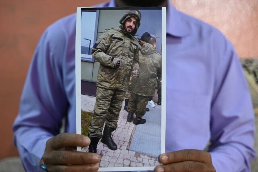 A photo of Indian national Mohammed Asfan in Russian military fatigues is held by his brot