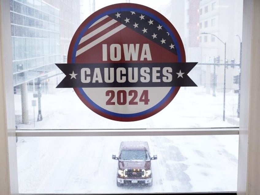 A pickup truck is driven down a snow covered road under an Iowa Caucus sign, Friday, Jan. 12, 2024, in downtown Des Moines, Iowa. (Charlie Neibergall/AP)