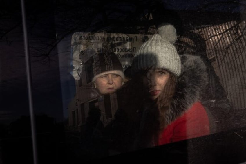 Anna (R), 21, and her mother (L) sit in a minivan as they wait at an evacuation point outs