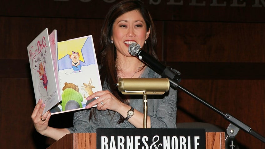 Kristi Yamaguchi holding up her book "Dream Big, Little Pig!"