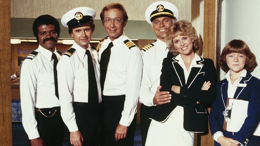 The cast of The Love Boat in costume and smiling with each other