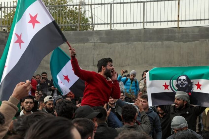 Syrians wave opposition flags, one with the portrait of late rebel fighter Abdel-Basset al