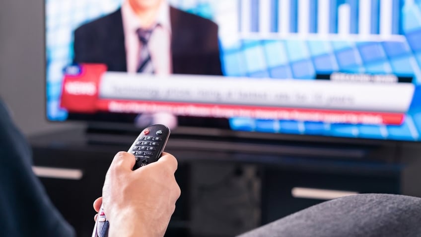 Man pointing a remote at a TV