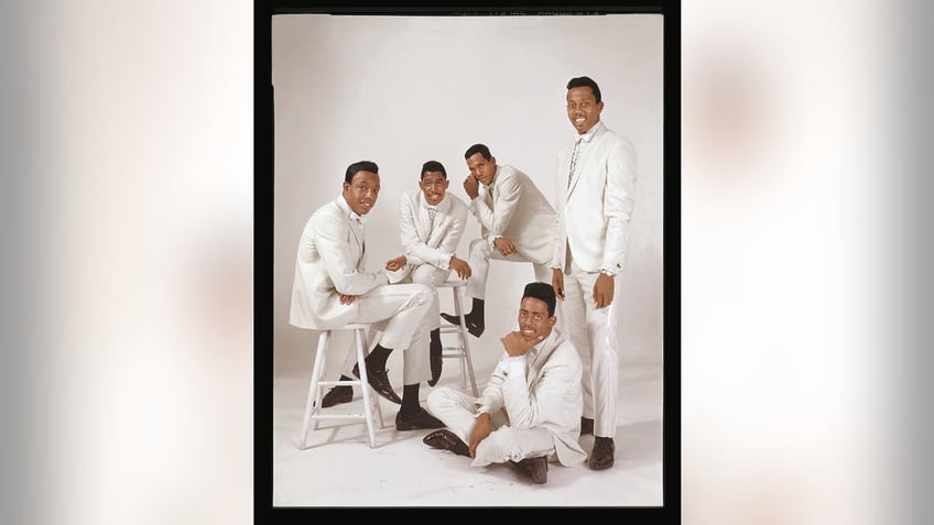 The Temptations wearing matching white suits.