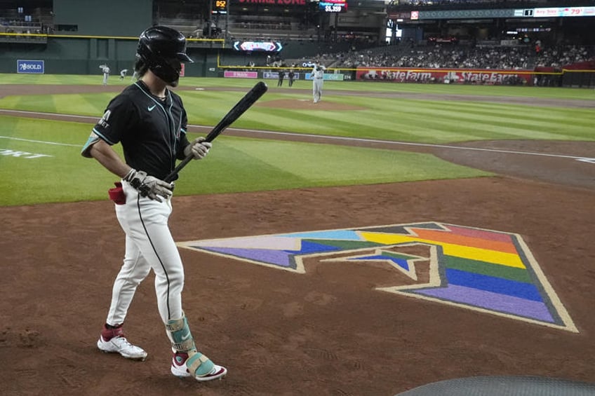Arizona Diamondbacks' Corbin Carroll walks past the Diamondbacks logo designed for Pride Night during the first inning of the team's baseball game against the Chicago White Sox, Friday, June 14, 2024, in Phoenix. (AP Photo/Ross D. Franklin)
