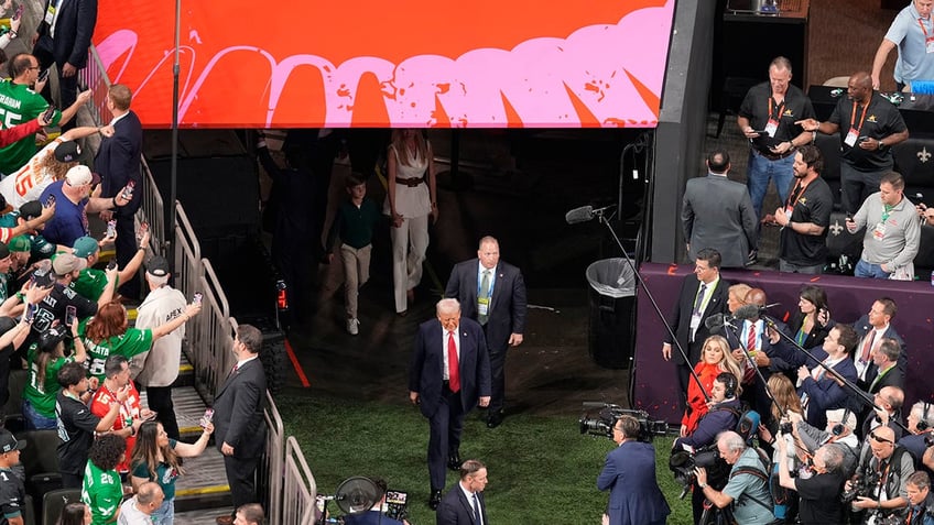 Onlookers watch Donald Trump walk on the field