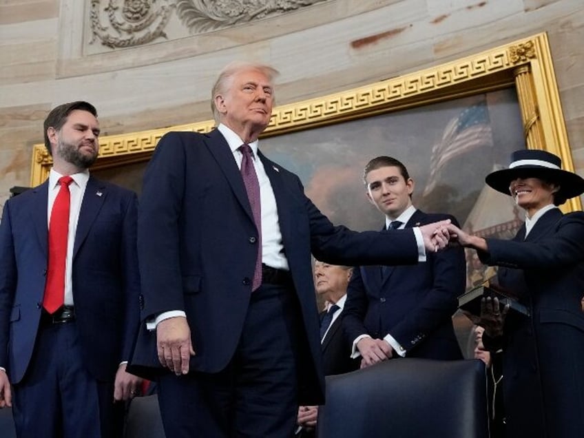 President Donald Trump, center, holds the hand of his wife Melania Trump, right, as their