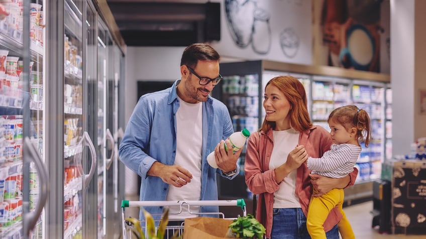 A father, mother and daughter shop for dairy items at a grocery store.