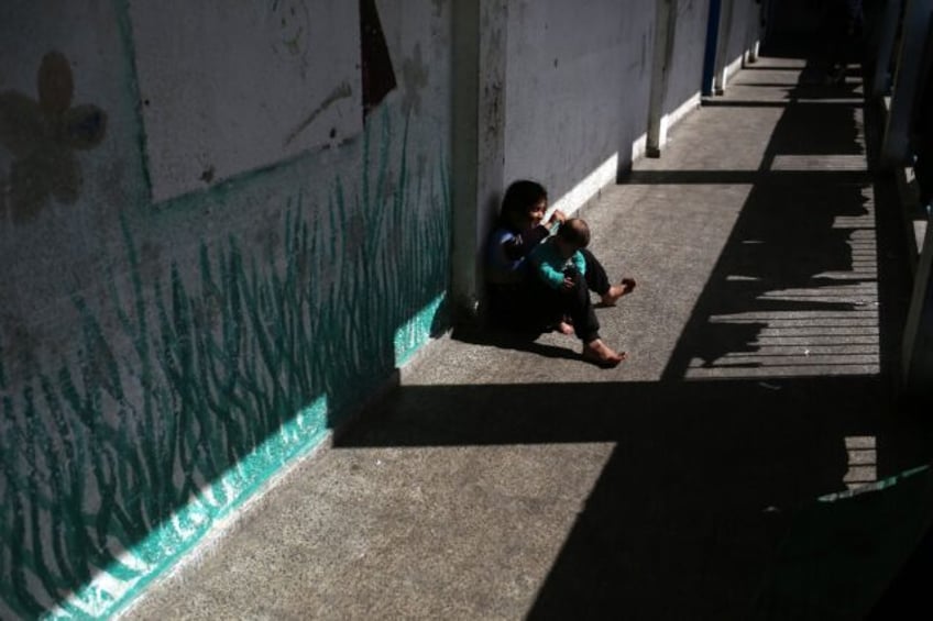 A girl brushes the hair of her sibling at a Gaza school now housing displaced families