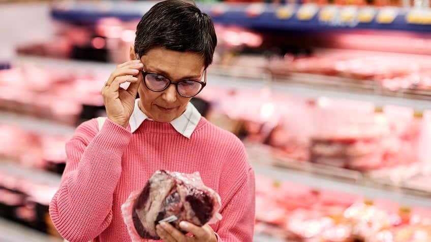 A woman in a grocery store looking at red meat