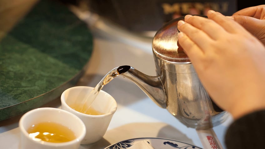 Green tea being poured into a tea cup