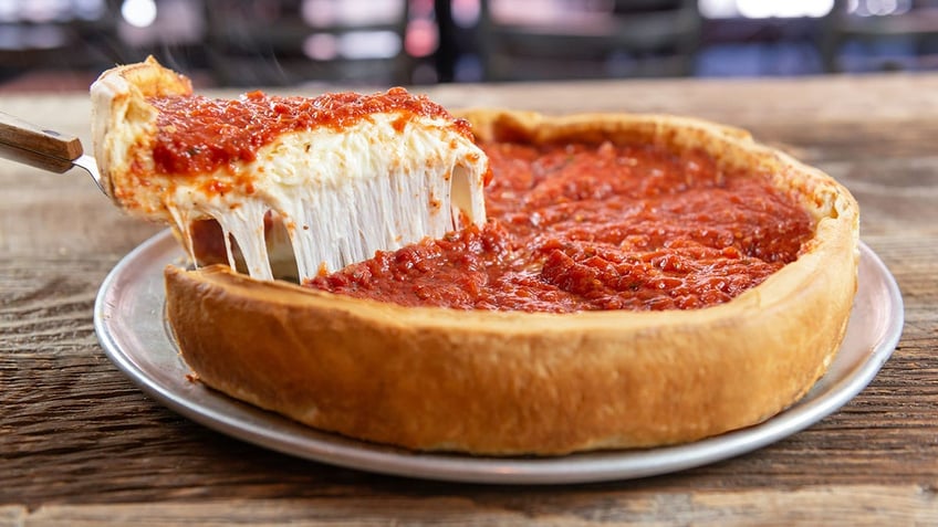 A picture of a slice of deep dish pizza being lifted out of the pie. It has a good cheese pull.