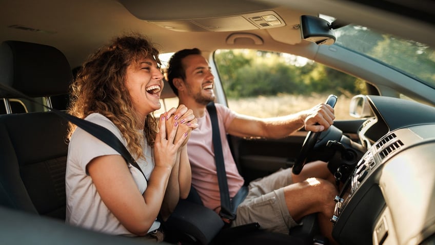 Young couple laughing during their adventurous car journey.