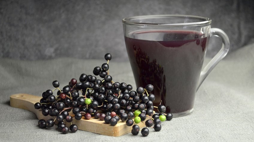 Elderberries next to glass of elderberry juice