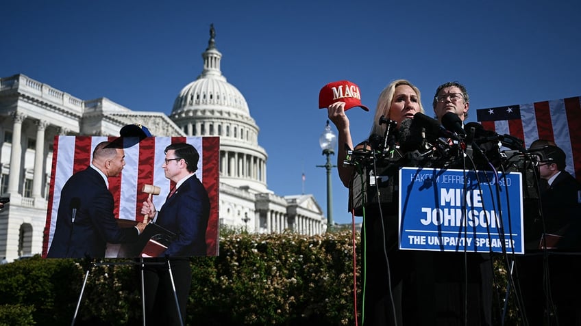 Massie and Greene outside the Capitol. Greene is holding a MAGA hat