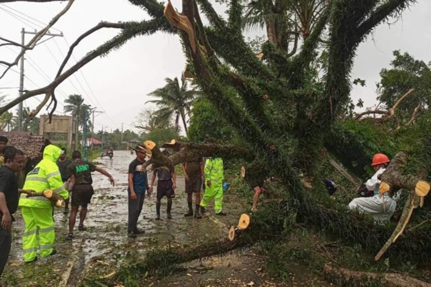 Government workers remove a fallen tree on a highway in Casiguran, Aurora province, after