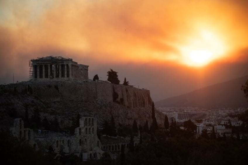 The Parthenon temple in Athens with a smoke cloud from a wildfire in the background. Thous