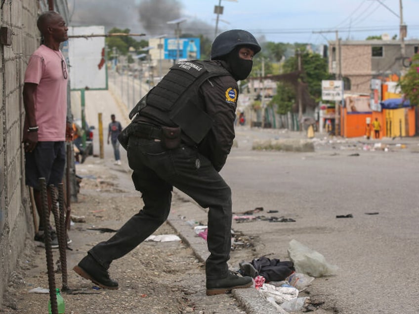 A police officer looks on during an exchange of gunfire between gangs and police in Port-a