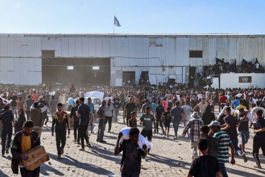 Displaced Palestinians ferry bags of food aid after storming a World Food Programme wareho