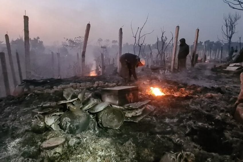 Rohingya refugees look through the debris of their houses charred by a devastating fire on Sunday