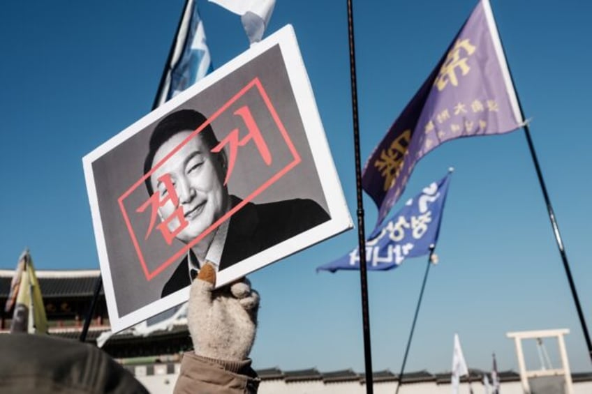 A protester walks with a portrait of impeached South Korean President Yoon Suk Yeol