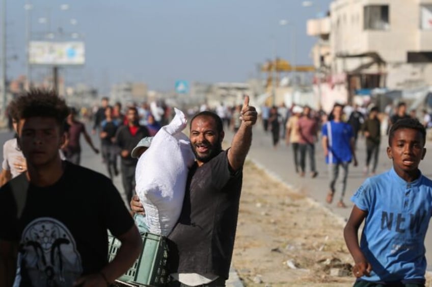 A man carries a bag of food aid while others rush to get a share after people stormed a Wo