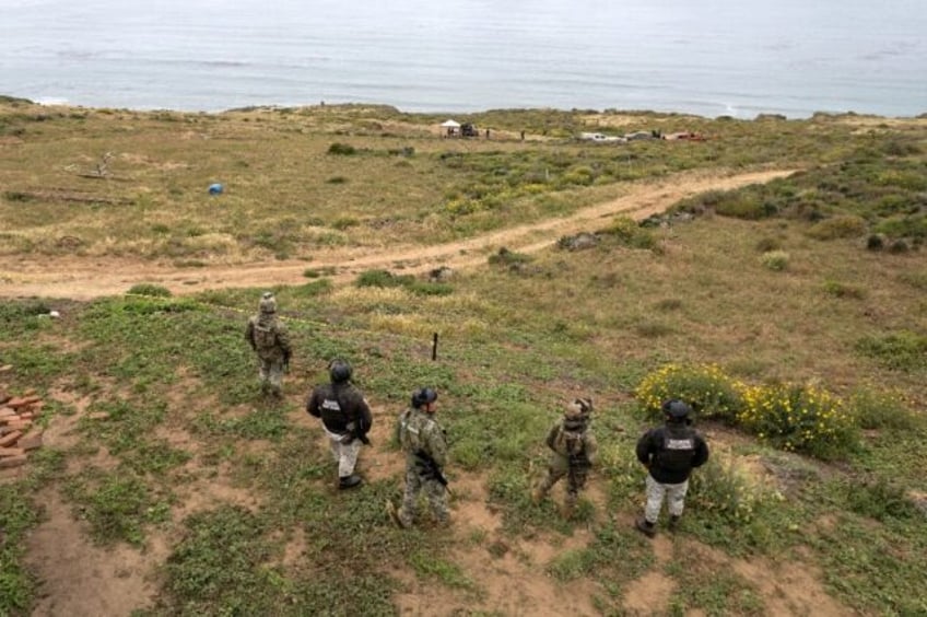 Mexican officers stand guard as rescue and forensics workers as well as prosecutors work a