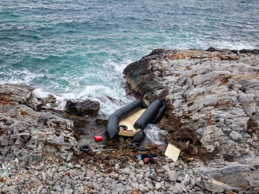 TOPSHOT - A rubber boat, believed to be used by migrants, lies destroyed on the rocky shor