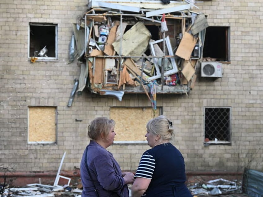 TOPSHOT - Women stand near a damaged residential building following a Russian drone strike