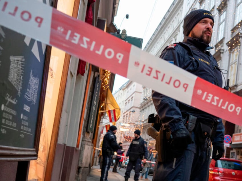 Austrian policemen stand guard at the site of a shooting outside Figlmueller passage in th